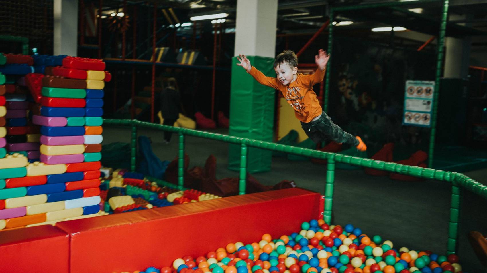 A child leaping into the soft play foam pit