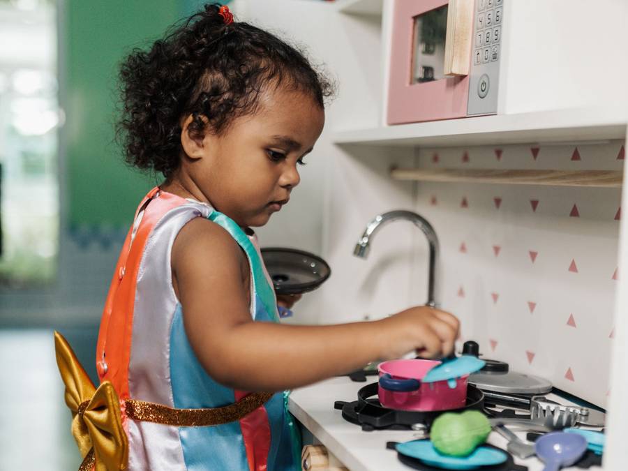 A toddler playing at the pretend kitchen